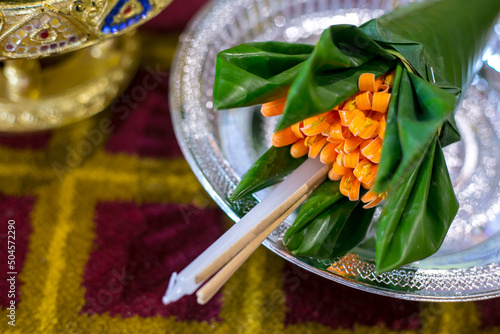 Orange trumpet, candle and incense sticks in banana leaf cones