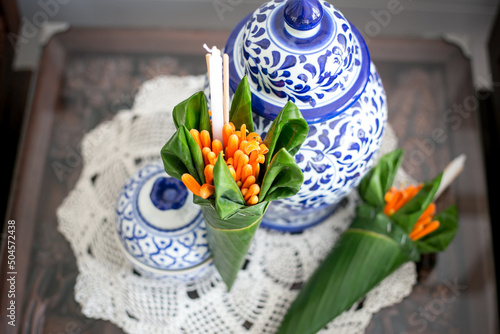 Orange trumpet, candle and incense sticks in banana leaf cones