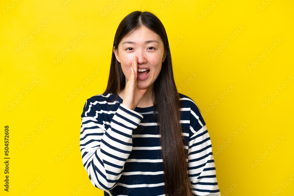 Young Chinese woman isolated on yellow background shouting with mouth wide open Young Chinese woman isolated on yellow background shouting with mouth wide open