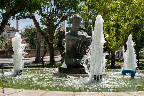 Fonte com repuxo de água e uma estátua de uma senhora a meio no parque de jardim em Mirandela, Portugal photo