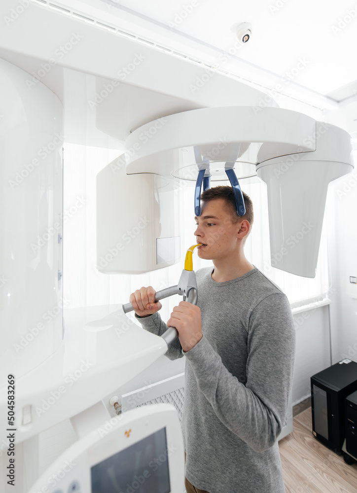 A young man has a computed tomography of the jaw, a circular snapshot of the jaw in modern dentistry. Prevention of caries, prosthetics and dental treatment. Radiology, panoramic scanner. A young man has a computed tomography of the jaw, a circular snapshot of the jaw in modern dentistry. Prevention of caries, prosthetics and dental treatment. Radiology, panoramic scanner.