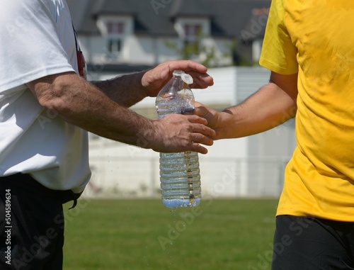 passage d'une bouteille d'eau au joueur de football	 photo