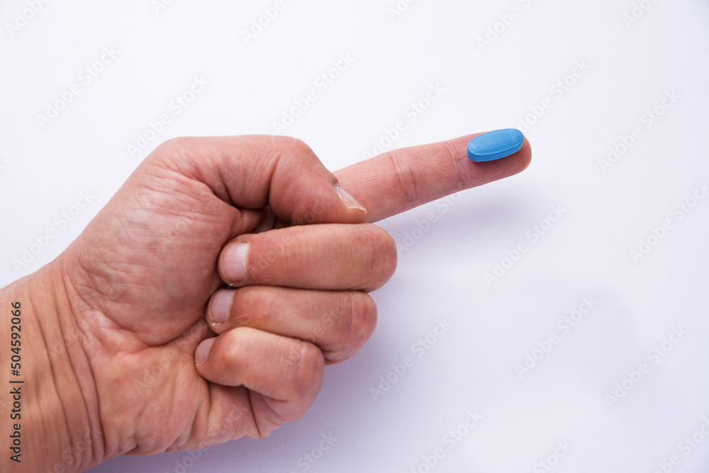 Male hand showing a blue pill on a finger Male hand showing a blue pill on a finger