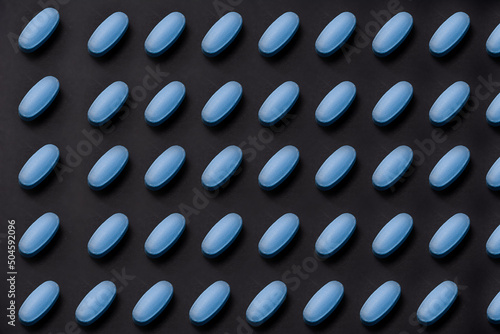 Ordered pattern of blue tablets on black background photo
