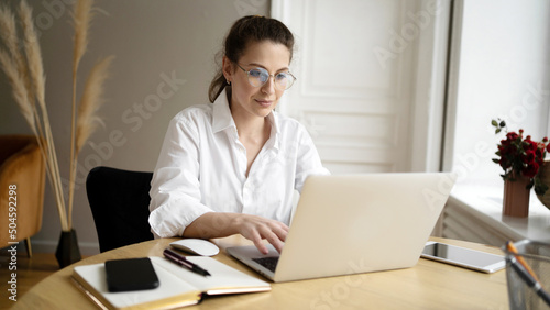 Foto A woman with glasses is a freelancer working in an office using a laptop, making