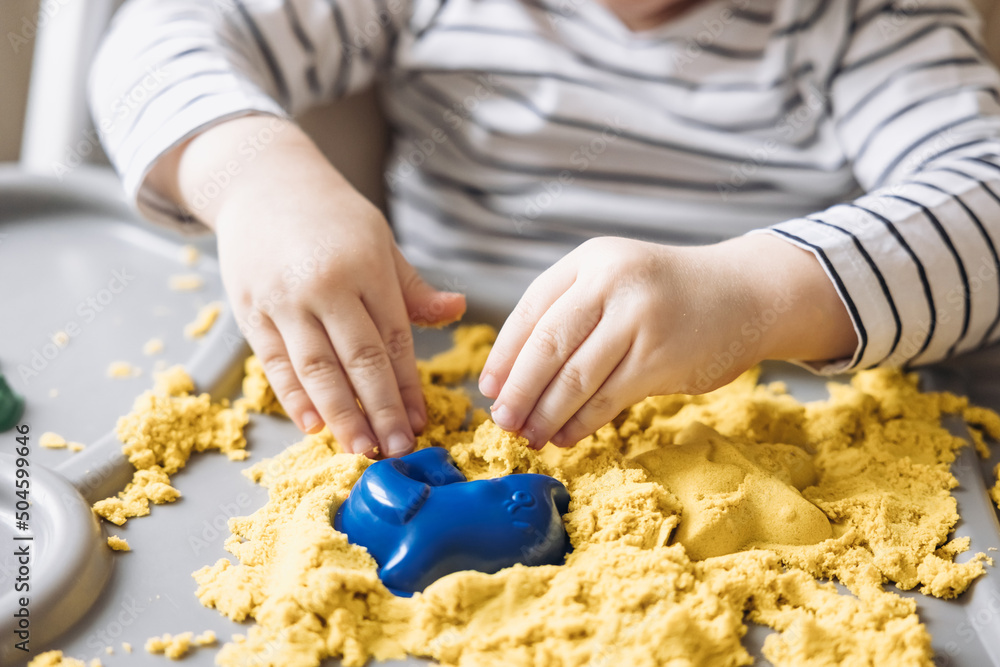Cute little boy playing with kinetic sand. Development of fine motor skills. Early sensory education. Activities Montessori. Sensory plays at home. Cute little boy playing with kinetic sand. Development of fine motor skills. Early sensory education. Activities Montessori. Sensory plays at home.