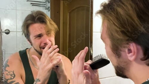 Happy guy singing with a hair brush in front of the mirror, concert in bathroom