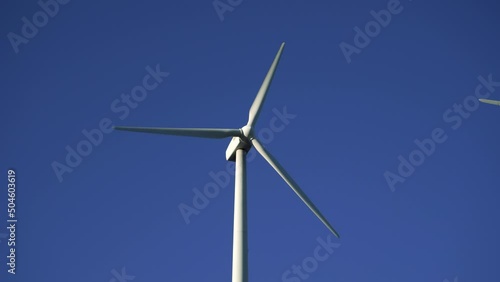 Wind turbines in a wind farm to get clean green energy through the air on top of a mountain on a sunny day. Fight against climate change through renewable energy. It is the future.