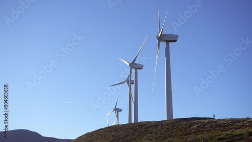 Wind turbines in a wind farm to get clean green energy through the air on top of a mountain on a sunny day. Fight against climate change through renewable energy. It is the future.