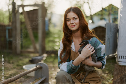 Young woman smiling for the camera holding a chicken and happy working on the farm © SHOTPRIME STUDIO