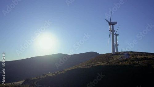 Wind turbines in a wind farm to get clean green energy through the air on top of a mountain on a sunny day. Fight against climate change through renewable energy. It is the future.