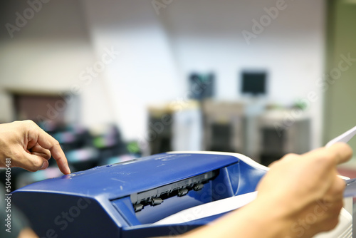 Technician hand press button and load paper in tray to using photocopier for scanning fax or photocopy or copy document after repairing paper jam or change toner cartridge in office workplace.