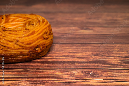 Italian traditional dish "Frittata di Pasta", pasta flan done with spaghetti and tomato sauce on a dark wood table. Selective focus with shallow depth of field