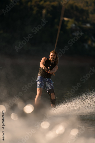 view on man holding rope and riding on the river wave on wakeboard