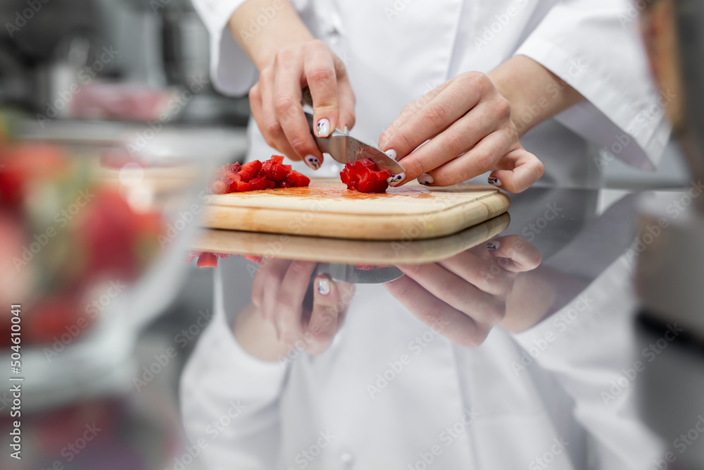 Close up of woman hands cutting strawberries on cutting board