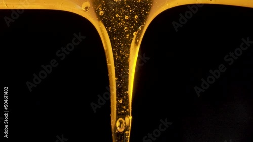 Drops of thick golden honey flowing down on a black background. Close up of sweet nectar or molasses being spilled. Liquid honey pours and drips. Sugar syrup is pouring. Healthy and curative dessert.