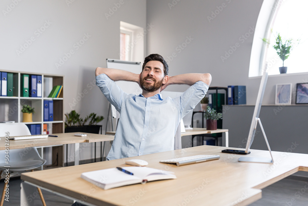 Businessman in the office dreamily resting throwing his hands behind his head, man working on a business project