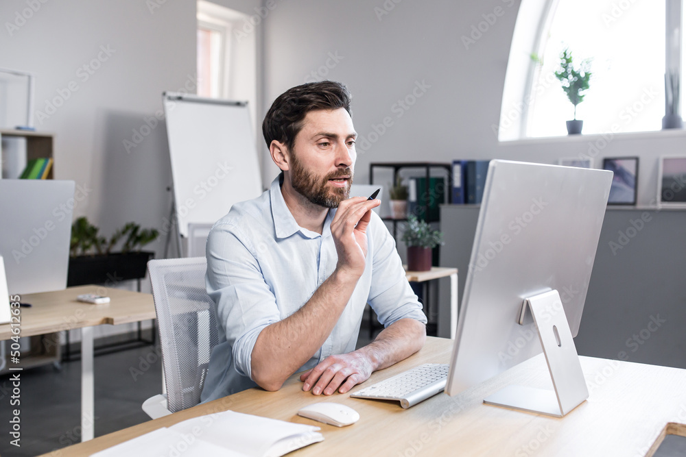 Freelancer looking at computer screen, man talking on video call, businessman in office working remotely Freelancer looking at computer screen, man talking on video call, businessman in office working remotely