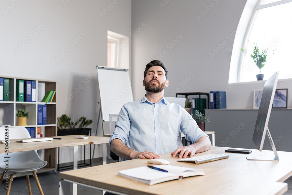 Businessman in the office with closed eyes performs breathing exercises, freelancer working on the computer Businessman in the office with closed eyes performs breathing exercises, freelancer working on the computer