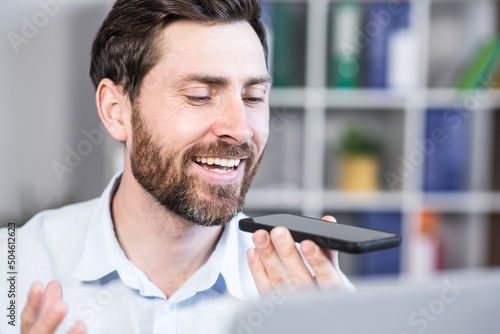 Tableau sur toile Cheerful and happy man records audio messages, freelance businessman in office,
