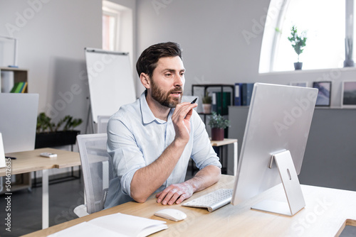 Freelancer looking at computer screen, man talking on video call, businessman in office working remotely