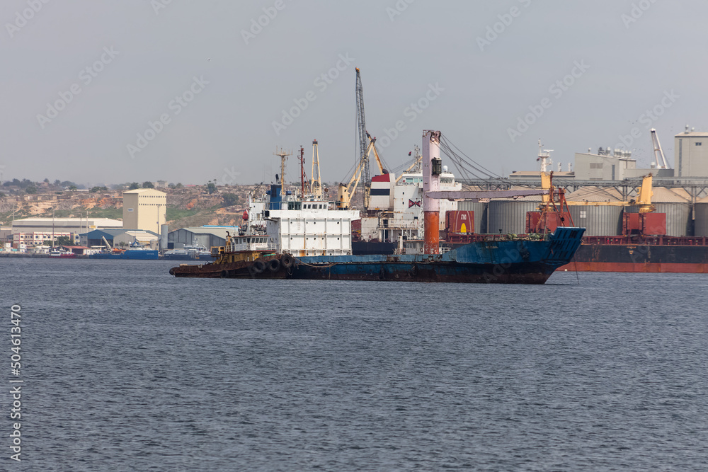 View of an oil tanker, ready to dock at the Port of Luanda, port logistics center with containers, equipment and machinery in the background, Luanda , Angola