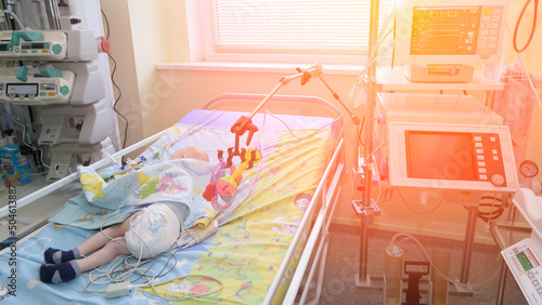 The child lies on a hospital bed and is connected to the resuscitator.