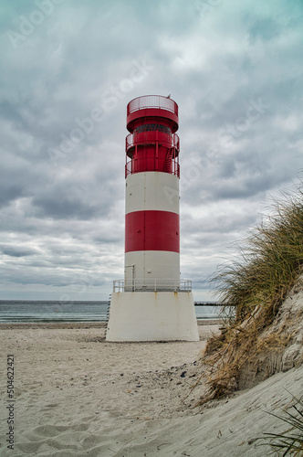 white and red lighthouse on the beach