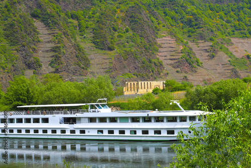 A cruise ship on the Moselle in Bremm with the Stuben monastery ruins in the background, Germany photo