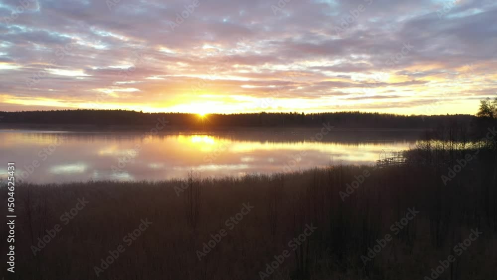 Flying Just Above Water Towards Forested Land Over Great Lakes at Sunrise. Beautiful lake at sunrise surrounded by forest and warm morning light. Evaporation over forest. A flock of birds taking off.