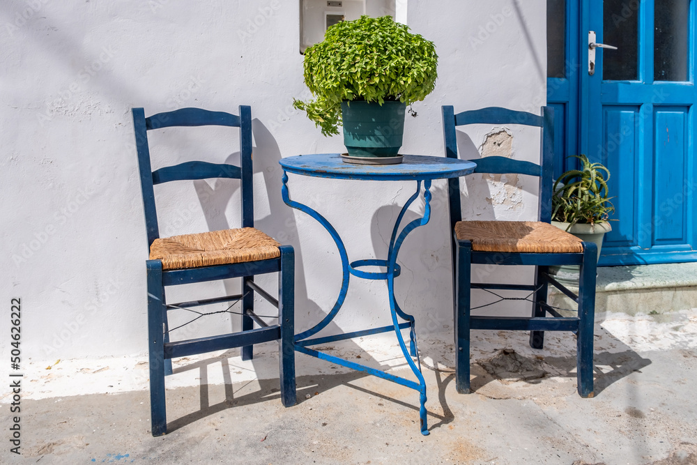 Empty round metal table and wood chair outdoor, Greek island Chora, Greece. Summer sunny day.