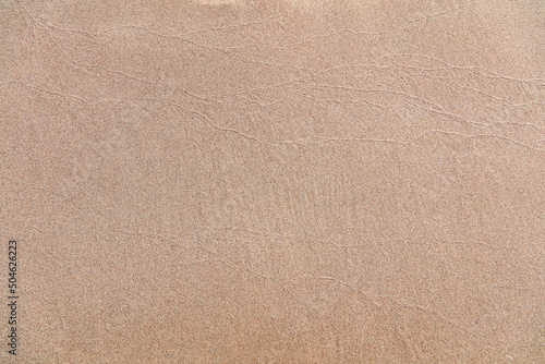 Wet sand texture background. Sandy beach close up top view, copy space. Summer vacation template