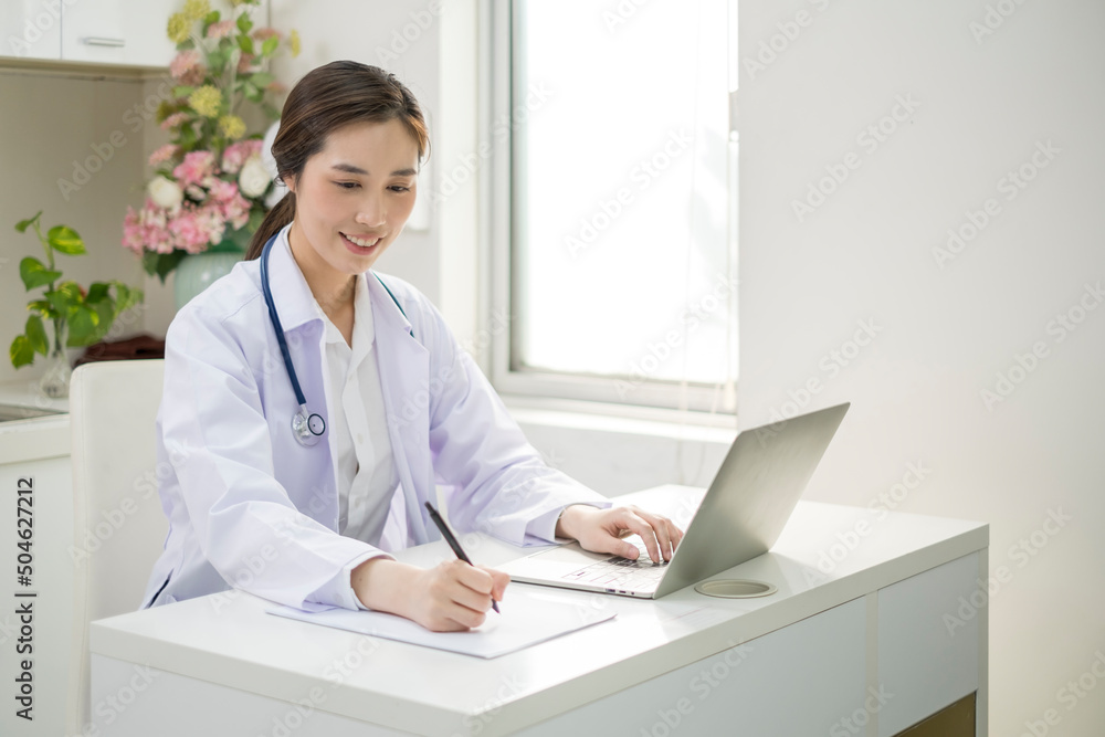Young Female Doctor in white coat sitting at her workplace working. Doctor sitting at desk and writing a prescription for her patient. Smiling female doctor working in doctor’s office. Young Female Doctor in white coat sitting at her workplace working. Doctor sitting at desk and writing a prescription for her patient. Smiling female doctor working in doctor’s office.