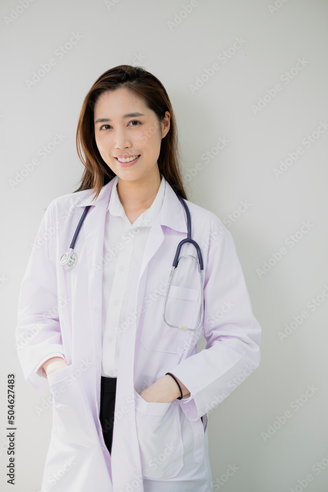 Smiling young woman Doctor is standing her office. Female Doctor with a stethoscope is standing in a clinic. Confident young adult female Doctor GP wear white coat and stethoscope. Smiling young woman Doctor is standing her office. Female Doctor with a stethoscope is standing in a clinic. Confident young adult female Doctor GP wear white coat and stethoscope.