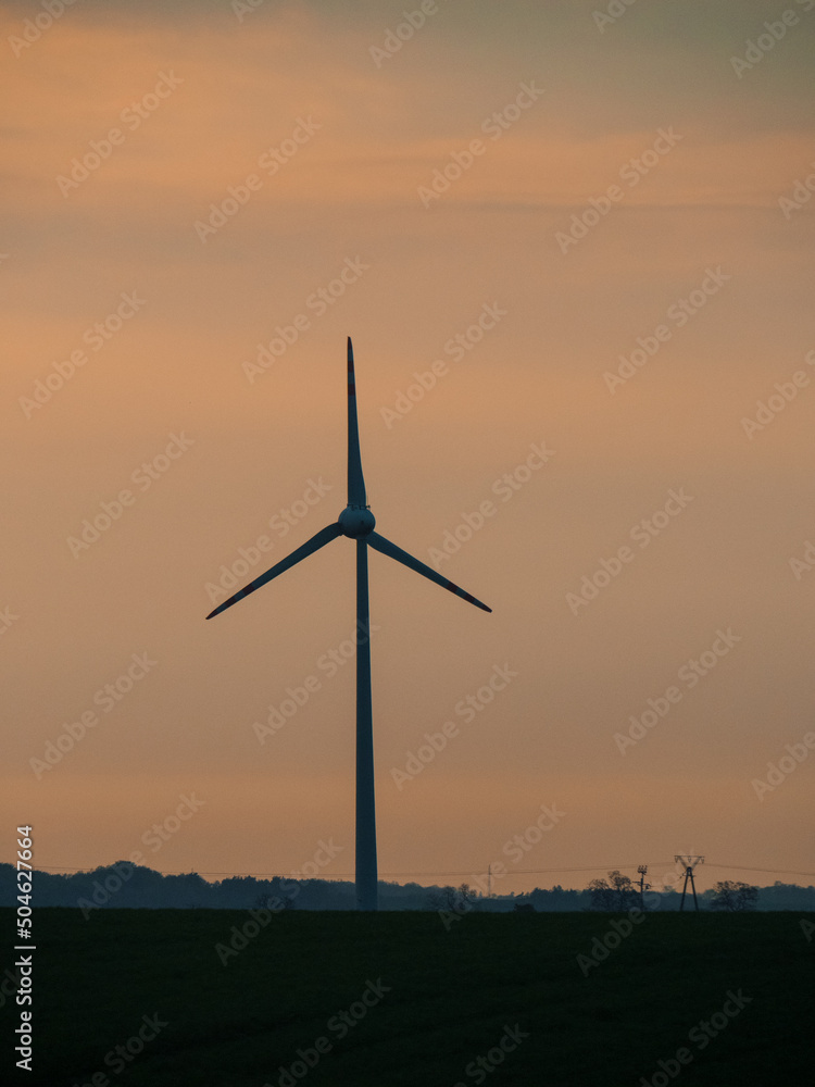 wind turbines in the field with green plants at sunset orange time wind turbines in the field with green plants at sunset orange time