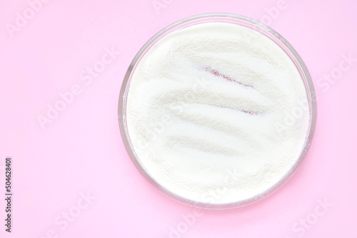 Collagen white powder. Pastel color background. Health product. Woman cosmetics concept. Sport supplement. Skincare cosmetics. Pink monochrome. Cream smear.