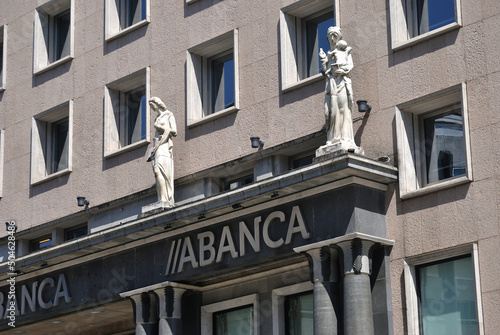 Parte do edifício de banco espanhol com logótipo, na frente e estátuas photo