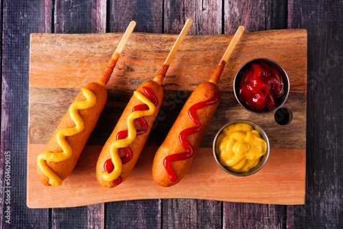 Photography Corn dogs with different toppings on a wooden platter