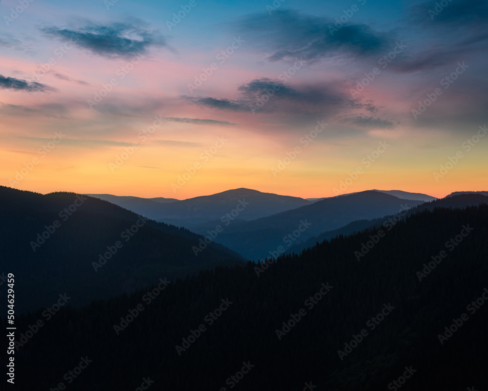 Beautiful landscape in the mountains at sunrise. View of mountains layers and colorful sky at distance in the twilight. Beautiful landscape in the mountains at sunrise. View of mountains layers and colorful sky at distance in the twilight.