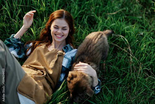 A woman lies on the grass smiling and cuddling her dog in nature in a park in the summer sunset. The concept of health and love for animals  treatment against ticks