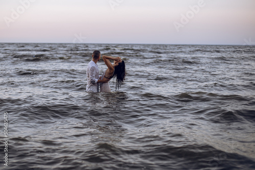 couple in love hugging in the sea at sunset