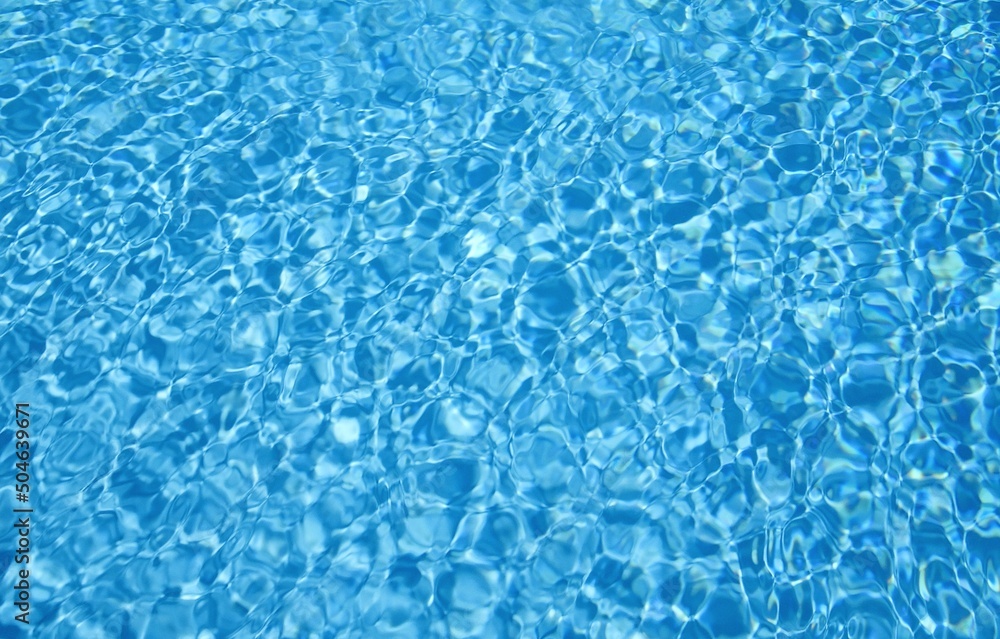 Blue water of a swimming pool. Sun reflection and ripple on blue water. Background of swimming pool water.