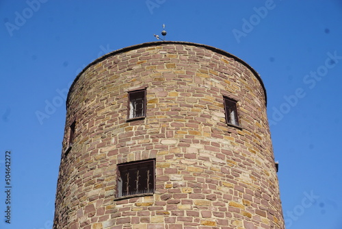 Alter braun-beiger Backsteinturm vor blauem Himmel bei Sonne im Frühling 