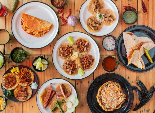 Mesa servida con tacos y varios platillos de comida mexicana, molcajete con carne al pastor al centro photo