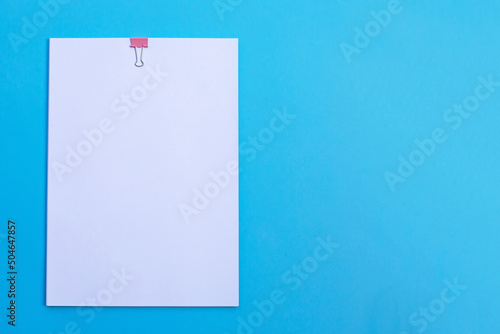 white paper with clip on blue background.