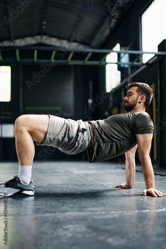 Athletic man doing reverse plank bridge exercise while working out in gym.