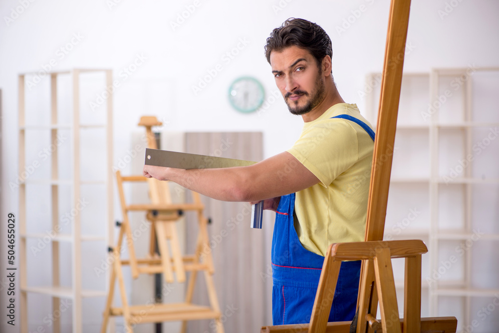 Young male repairman repairing easel at home Young male repairman repairing easel at home