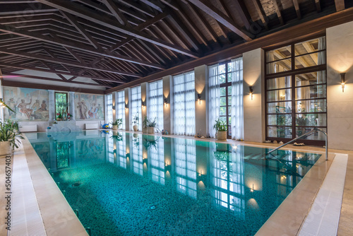 Stylish interior of a country house with a large azure swimming pool.
