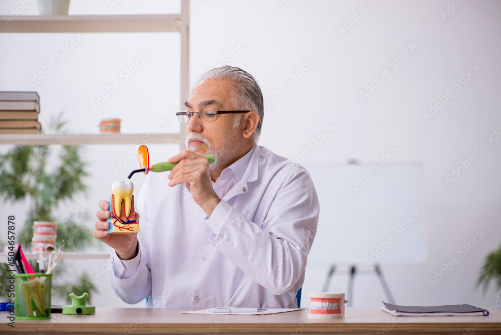 Old male dentist working in the clinic Old male dentist working in the clinic