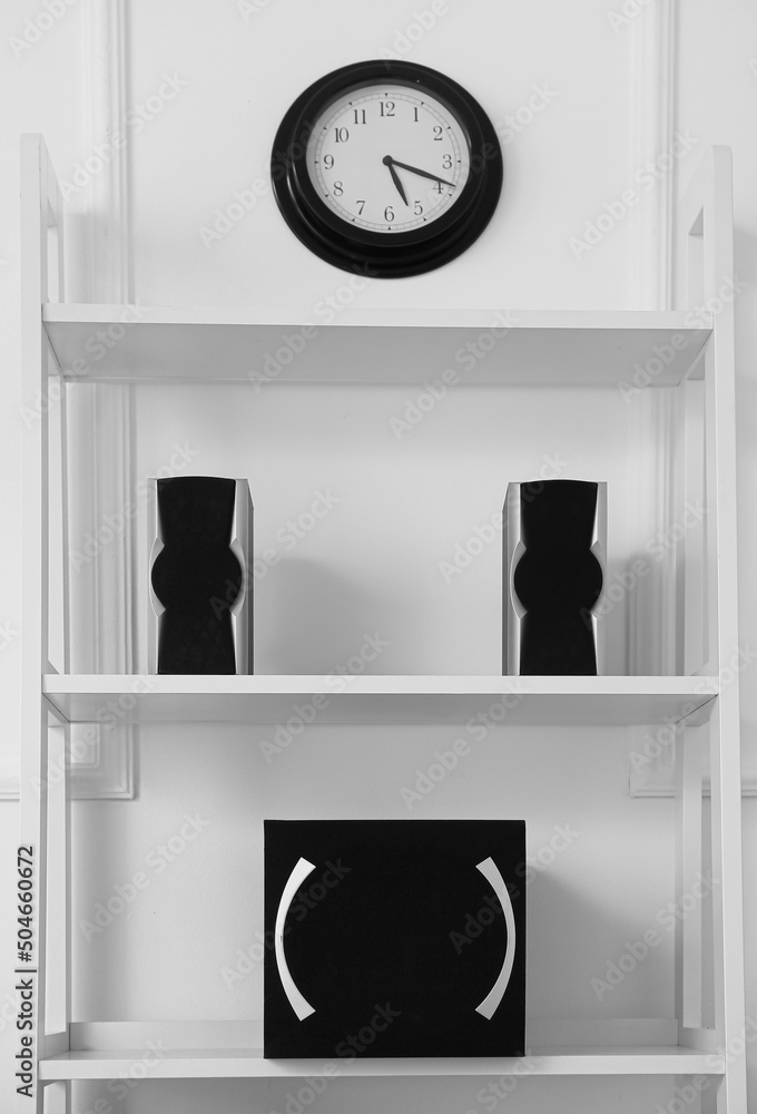 Shelf unit with modern speakers and clock on white wall Stock